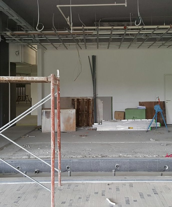  Baustelle mit Gerüst, leerem Raum und verschiedenen Baumaterialien im Hintergrund.